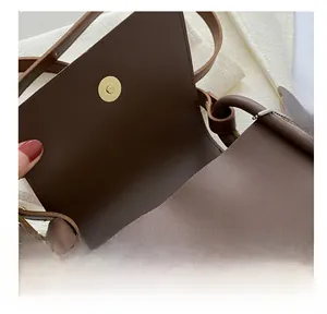 Detail of dual magnetic snap closures in vintage gold on a brown leather shoulder bag