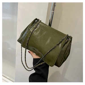 Detail of moss green wrinkled patent leather bag with chain strap and text