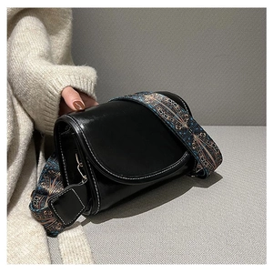 Close-up of black crossbody bag with white stitching and colorful ethnic patterned strap