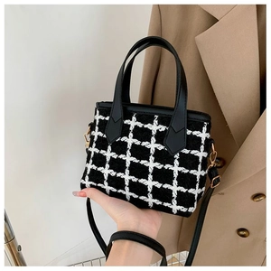 Close-up of black and white tweed bucket bag with leather handle and elegant texture