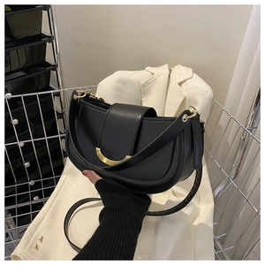 Détail du sac selle noir avec grande boucle dorée sur fond de blazer blanc élégant