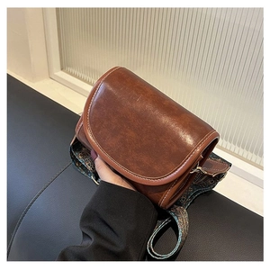 Close-up of brown retro shoulder bag with white stitching and embroidered strap