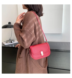 Detail of dark red leather crossbody bag with gold metal buckle on female model