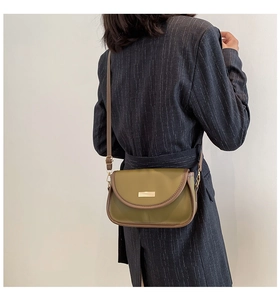 Retro olive green saddle bag with brown trim shown from the back on a model suit