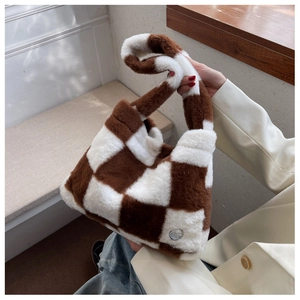 Détail du sac cabas en peluche à carreaux montrant la fourrure douce et le logo en métal