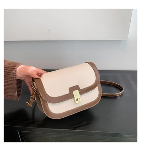 Detail of a vintage-style crossbody bag with cream and brown patchwork and gold lock
