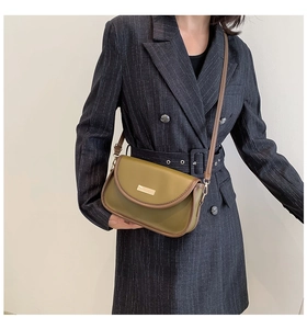 Detail of olive green leather crossbody bag featuring gold buckle and brown leather strap
