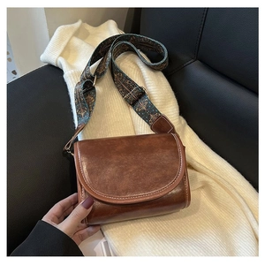 Detail of vintage brown crossbody bag with contrast stitching and patterned jacquard strap