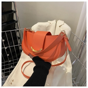 Détail du sac selle orange avec boucle en métal doré et texture en cuir de qualité