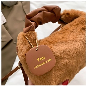 Close-up of brown faux fur handbag featuring ruched leather handle and branded tag