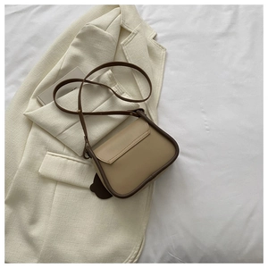 Detail of khaki faux leather shoulder bag with brown edges on tweed blazer