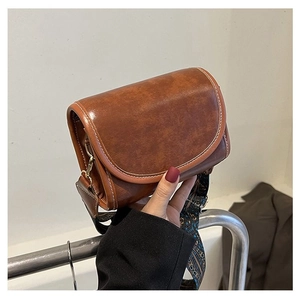 Detail of vintage brown leather crossbody bag featuring contrast stitching and ethnic strap
