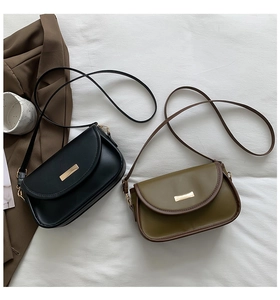 Minimalist black and olive green crossbody bags with gold buckles on fabric background