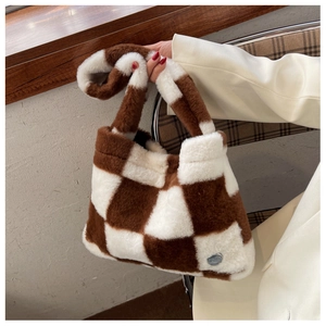 Détail du sac cabas en peluche avec motif damier marron et blanc et plaque logo en métal