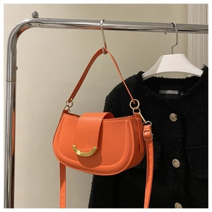 Détail du sac selle orange avec boucle en métal doré et texture en cuir lisse