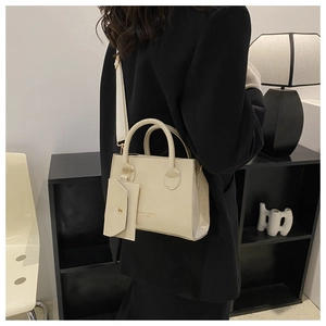Detail of cream leather handbag with adjustable wide strap and mini hanging pouch