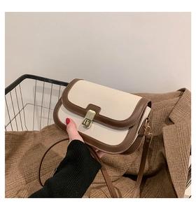 Detail of retro cream and brown leather bag with a gold square twist lock and slim strap