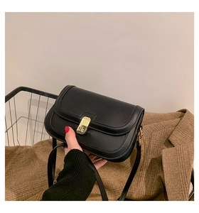 Detail of a black matte leather crossbody bag with a sleek gold rectangular twist-lock