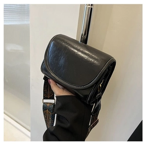 Detail view of black matte leather saddle bag with white stitching and retro strap