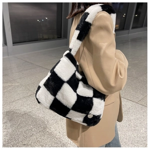 Détail d'un sac cabas à damier en peluche montrant la texture douce et le logo en métal