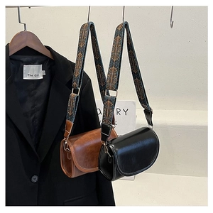 Close-up of saddle bag featuring a wide bohemian style jacquard strap and leather finish