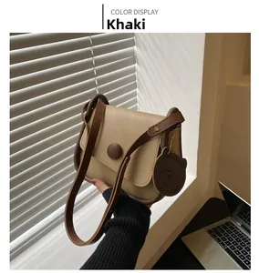 Detail of khaki square crossbody bag with round buckle and cute bear charm pendant