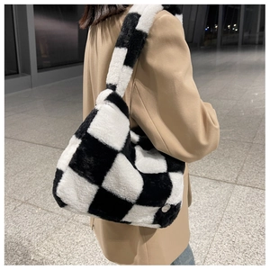 Gros plan du sac cabas en peluche damier noir et blanc porté à l'épaule