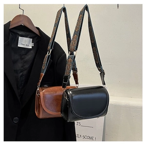 Detail of minimalist bags with white contrast stitching and ethnic embroidery straps