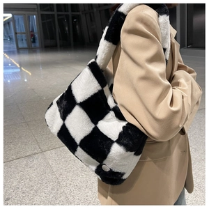 Détail d'un sac cabas en peluche à damier avec logo métallique et texture en fausse fourrure