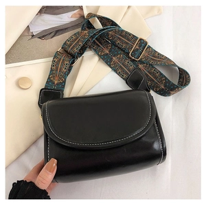 Detail of black leather crossbody bag featuring bohemian embroidery on wide strap