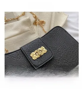 Détail du sac bandoulière en cuir noir avec fermoir en métal doré à motif tressé