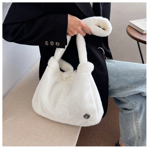 Gros plan détaillé d'un sac à main blanc en peluche avec logo en métal et texture douce