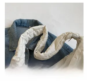 Detail of white quilted padded shoulder strap with glossy finish on denim background