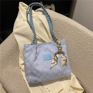 Light blue quilted tote bag with woven handles and silk scarf on cream blazer