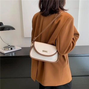 Minimalist cream white crossbody bag with brown trim and metallic detail on a model