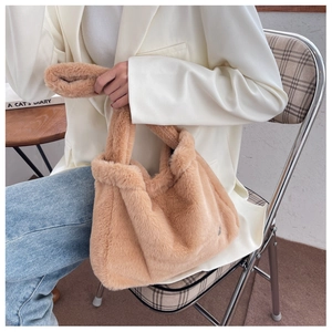 Détail de la texture en fausse fourrure douce d'un grand sac cabas en peluche beige