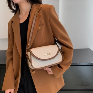 Vintage cream and brown crossbody bag with gold buckle on female model in brown suit