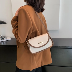 Minimalist beige and brown contrast crossbody bag with gold buckle on shoulder