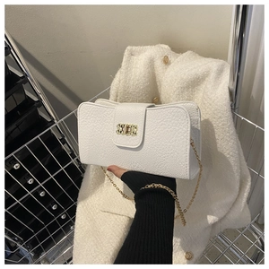 Détail du sac en cuir blanc grainé avec chaîne dorée et fermoir rotatif en métal
