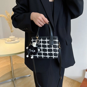 Fashionable black and white tweed bucket bag with a plush charm and shoulder strap