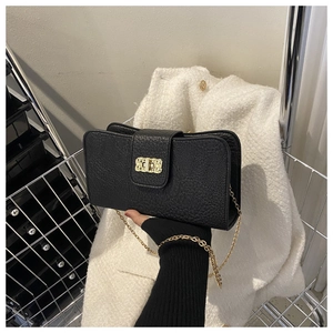 Détail d'un sac noir en cuir grainé avec bandoulière chaîne et boucle dorées vintage