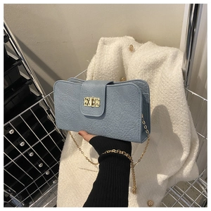 Détail du sac à bandoulière bleu clair motif litchi avec fermoir doré et bandoulière chaîne