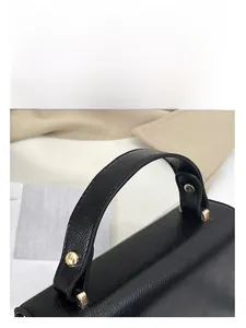 Detail of black leather handbag featuring fine lychee texture and gold rivet hardware