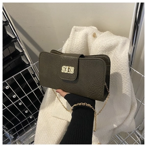 Détail du sac bandoulière vert foncé texture litchi avec chaîne dorée et fermoir carré