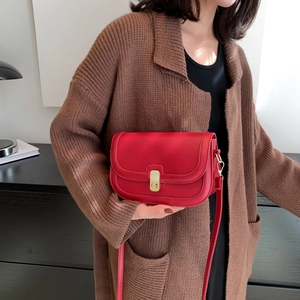 Vintage red leather crossbody bag with gold buckle on elegant dark knit cardigan outfit