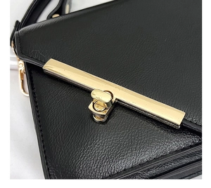 Detail of black leather small square bag with polished gold metal twist lock closure