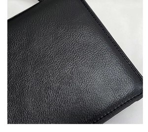 Close-up of premium black lychee pattern leather texture with neat stitching on square bag