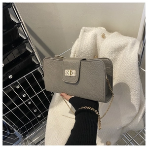 Détail du sac à bandoulière gris texture litchi avec fermoir rotatif doré et chaîne