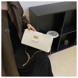 Gros plan sur la texture cuir litchi blanc et le fermoir tournant doré du sac à main