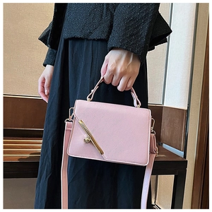Detail of light pink textured leather handbag with gold metal clasp on black coat